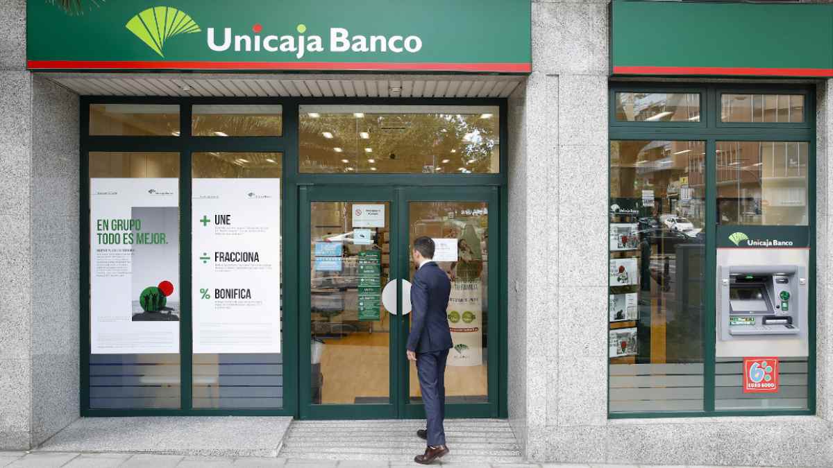 Sucursal de Unicaja Banco con un cliente entrando, relacionada con la bonificación de hasta 450 euros por domiciliar ingresos.