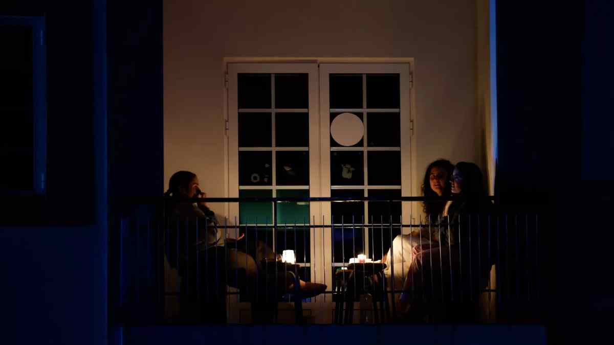 Personas en un balcón iluminado con velas durante un apagón eléctrico en España.