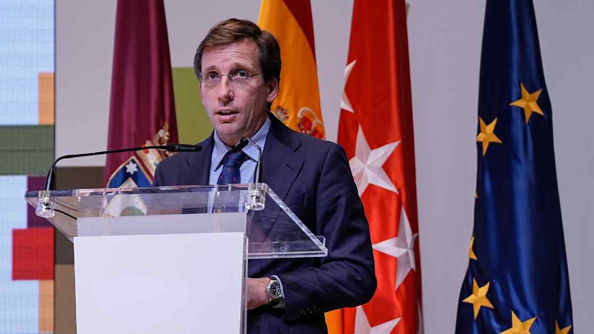 Responsable público hablando en un acto institucional con banderas oficiales de fondo.