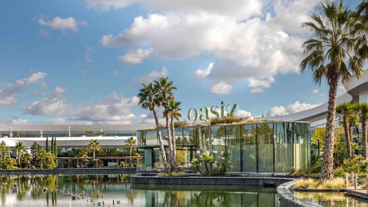 Fachada del centro comercial Oasiz en Torrejón de Ardoz reflejada en el lago.