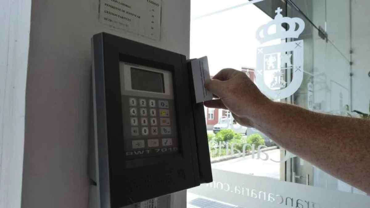 Trabajador fichando en un sistema de control horario antes de la apertura del negocio.