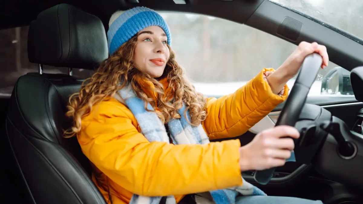 Mujer conduciendo con abrigo de invierno al volante, situación que puede ser sancionable según la DGT.