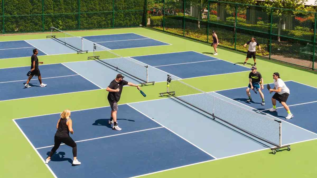 Personas jugando al pickleball en pistas exteriores de una instalación deportiva.