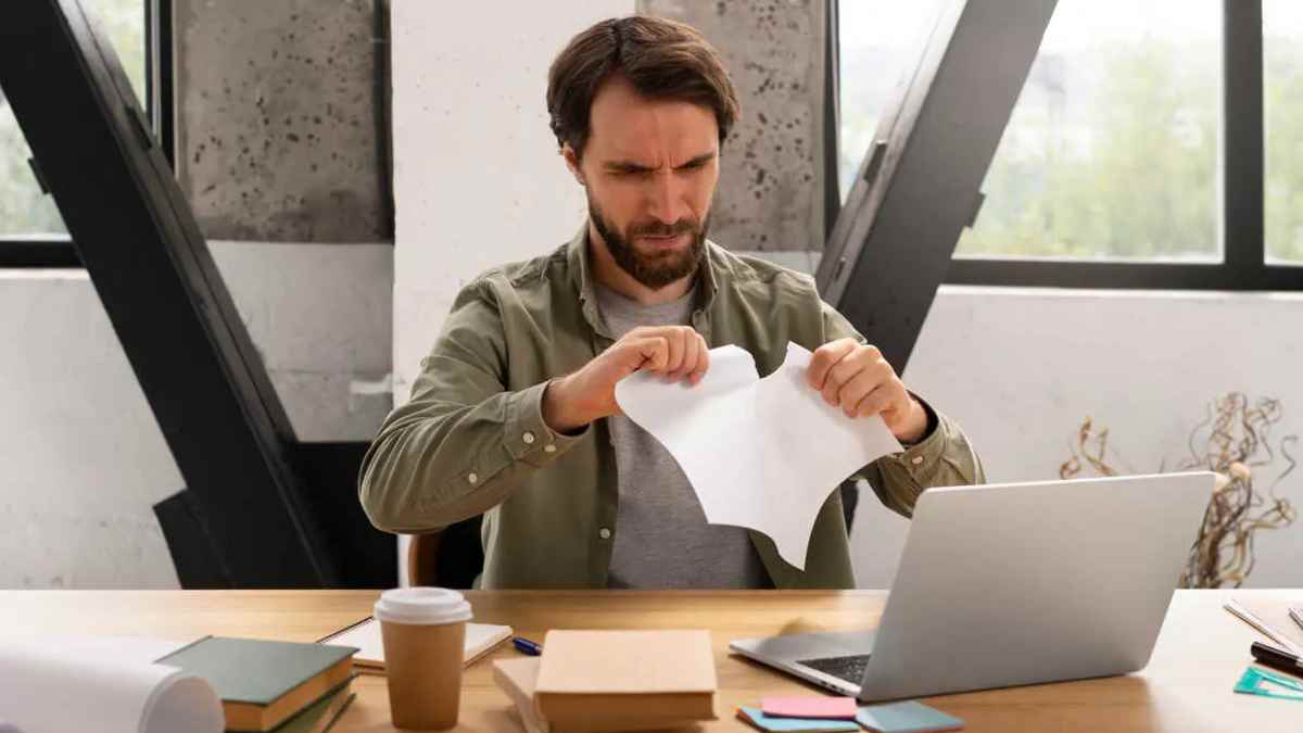 Autónomo frustrado rompiendo un documento por errores en trámites con Hacienda