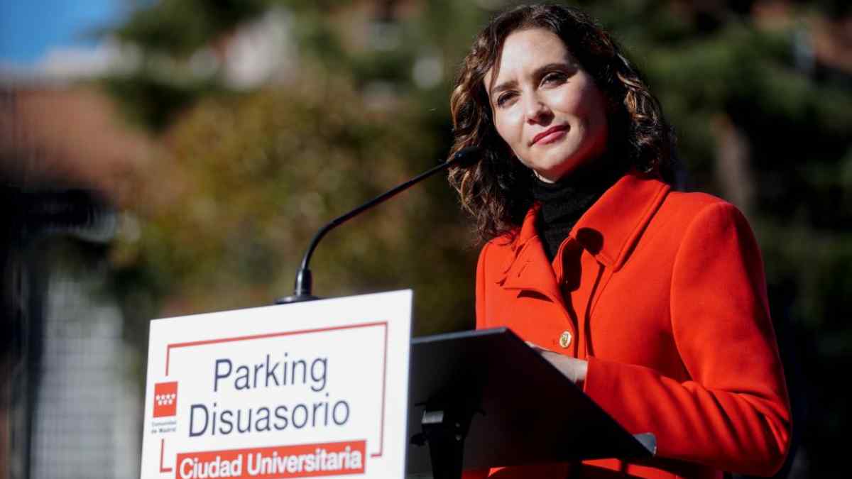 Ayuso en acto sobre aparcamiento disuasorio en Madrid junto a cartel de Parking Disuasorio de Ciudad Universitaria.