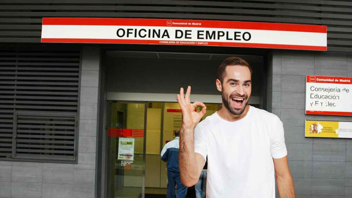 Hombre frente a una oficina de empleo mostrando gesto de aprobación.