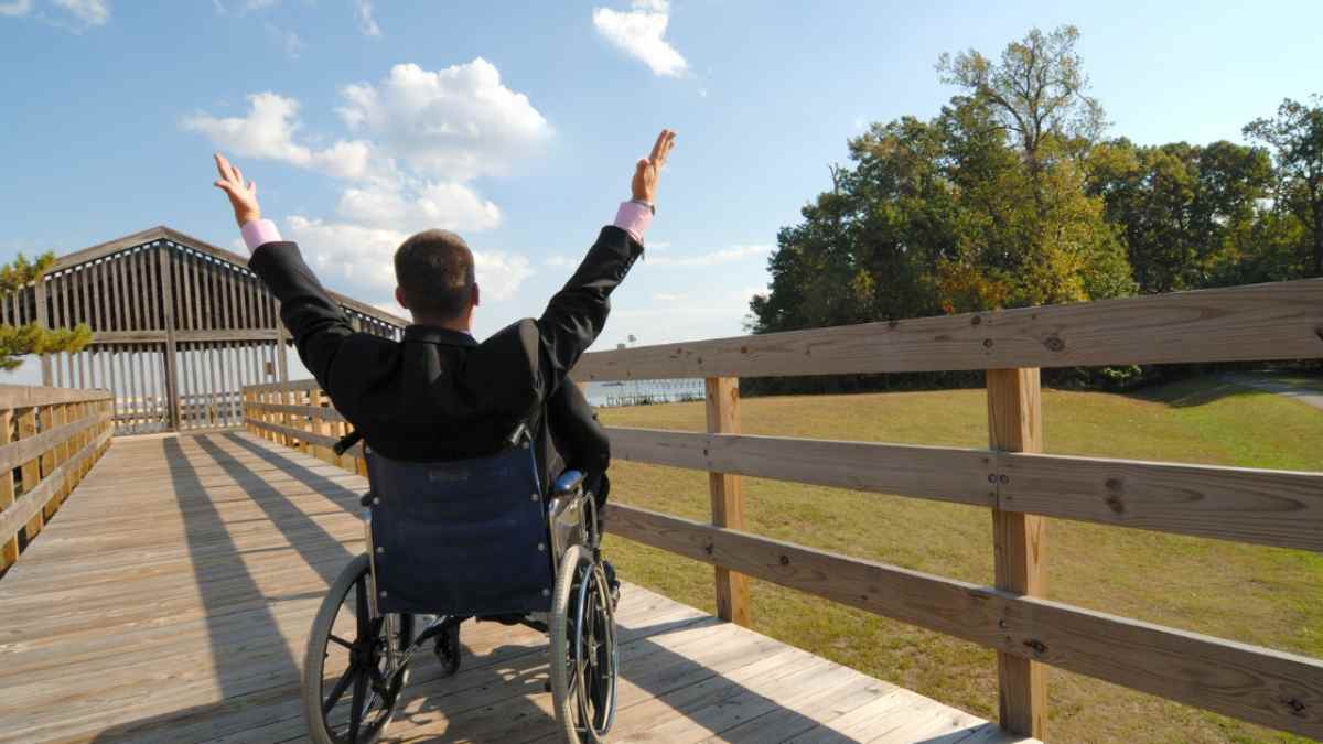 Hombre en silla de ruedas celebrando al aire libre tras ganar sentencia por pensión de discapacidad.