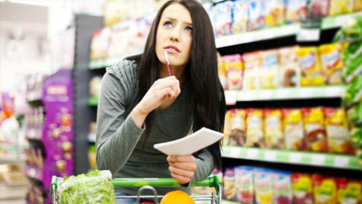 Mujer comparando precios en el supermercado para ahorrar en la compra semanal