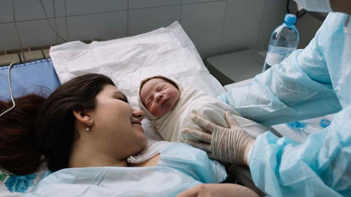 Madre con su bebé recién nacido tras el parto, imagen relacionada con las ayudas por nacimiento o adopción