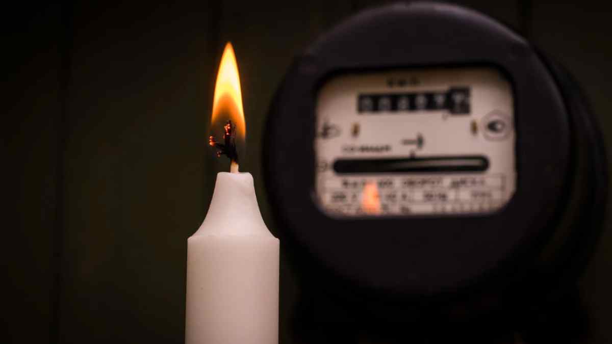 Vela encendida junto a un contador eléctrico por la subida del precio de la luz en enero
