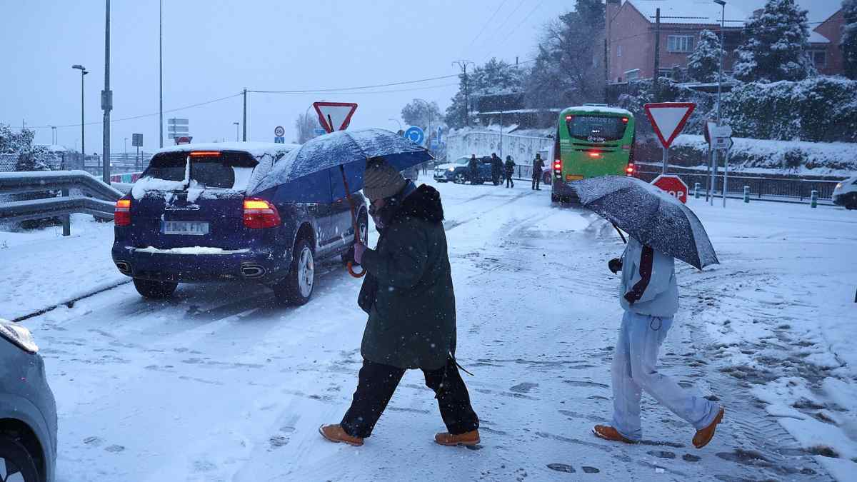 Trabajadores caminando por una calle nevada durante una alerta meteorológica que dificulta el acceso al trabajo