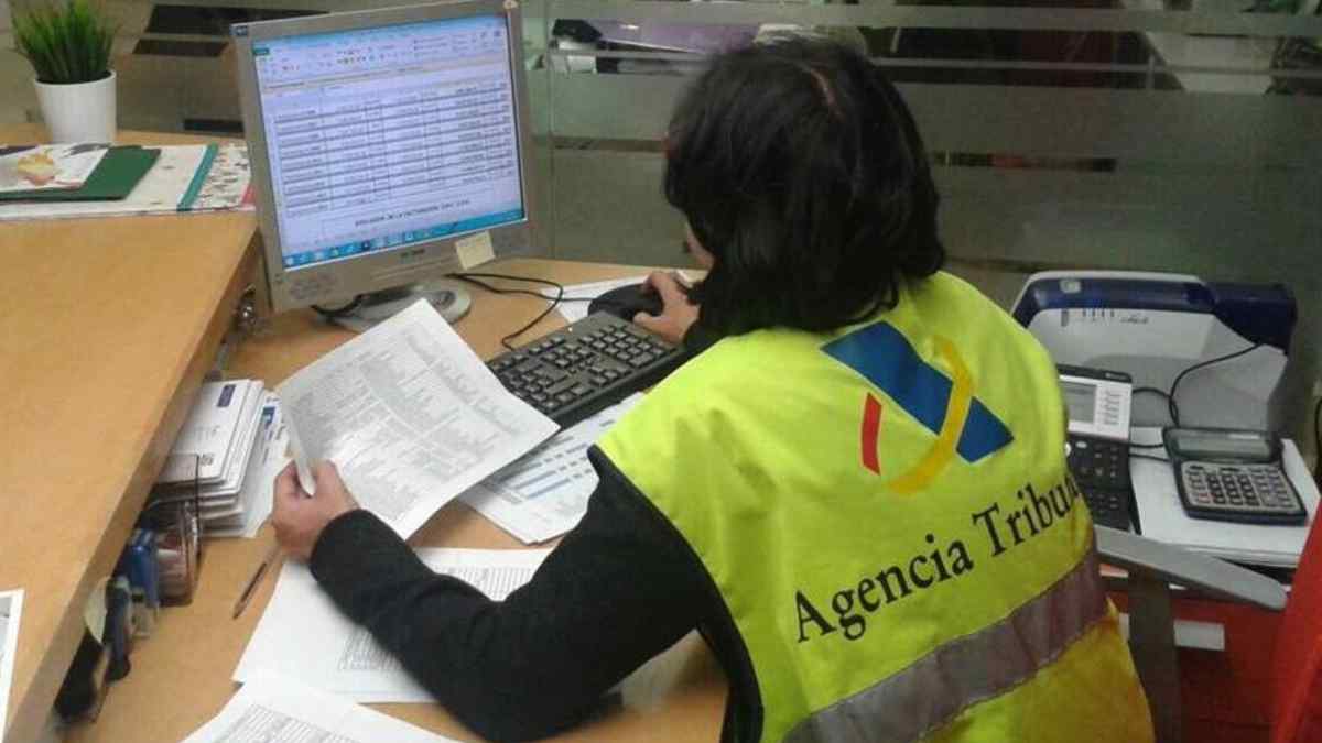 Empleada de la Agencia Tributaria revisando documentos sobre impuestos por vivienda cedida a un hijo