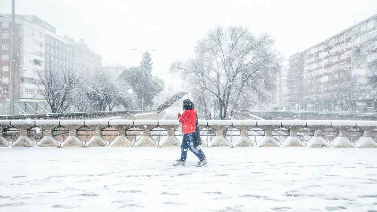 Persona caminando bajo la nieve en Madrid durante el aviso amarillo de AEMET por nevadas