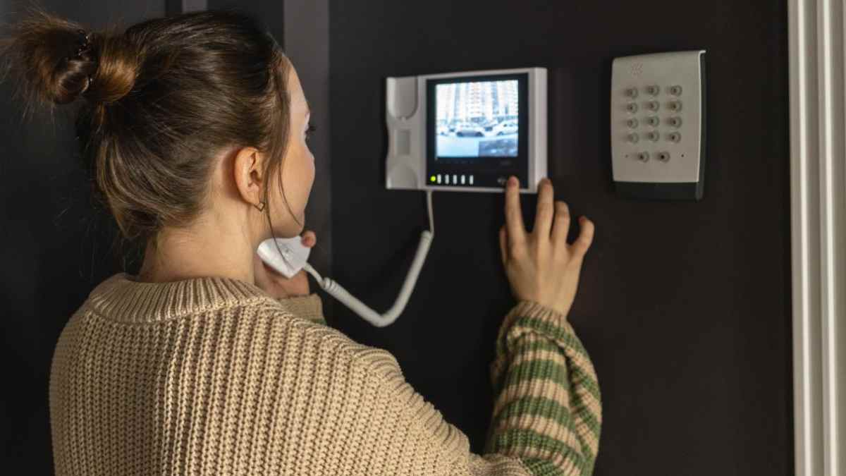 Mujer utilizando el telefonillo de su vivienda en un edificio de vecinos