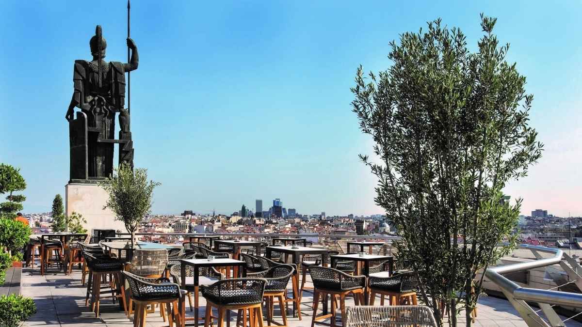 Terraza del Círculo de Bellas Artes en Madrid con mesas, una gran escultura y vistas panorámicas de la ciudad