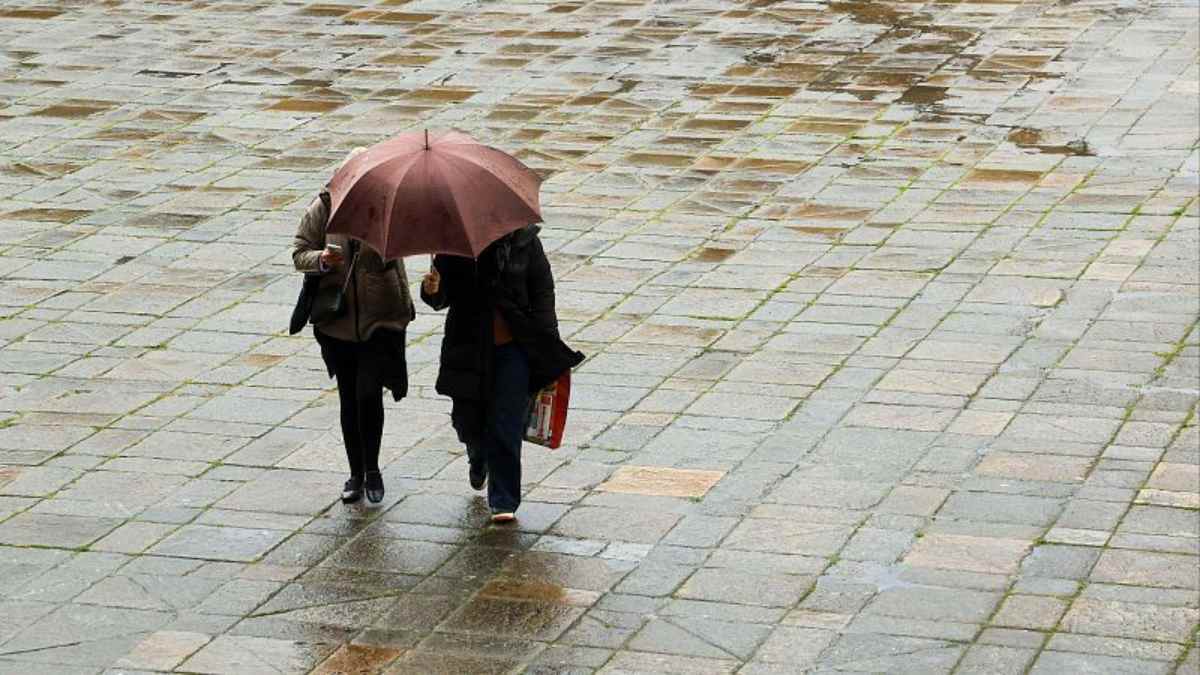 Personas caminando bajo la lluvia en Madrid en un lunes gris con cielos cubiertos y ambiente invernal