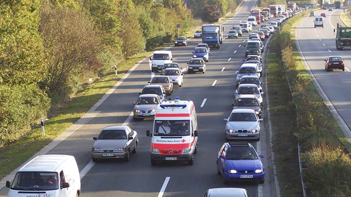 Ambulancia circulando por pasillo de emergencia en un atasco en carretera tras nueva norma de la DGT