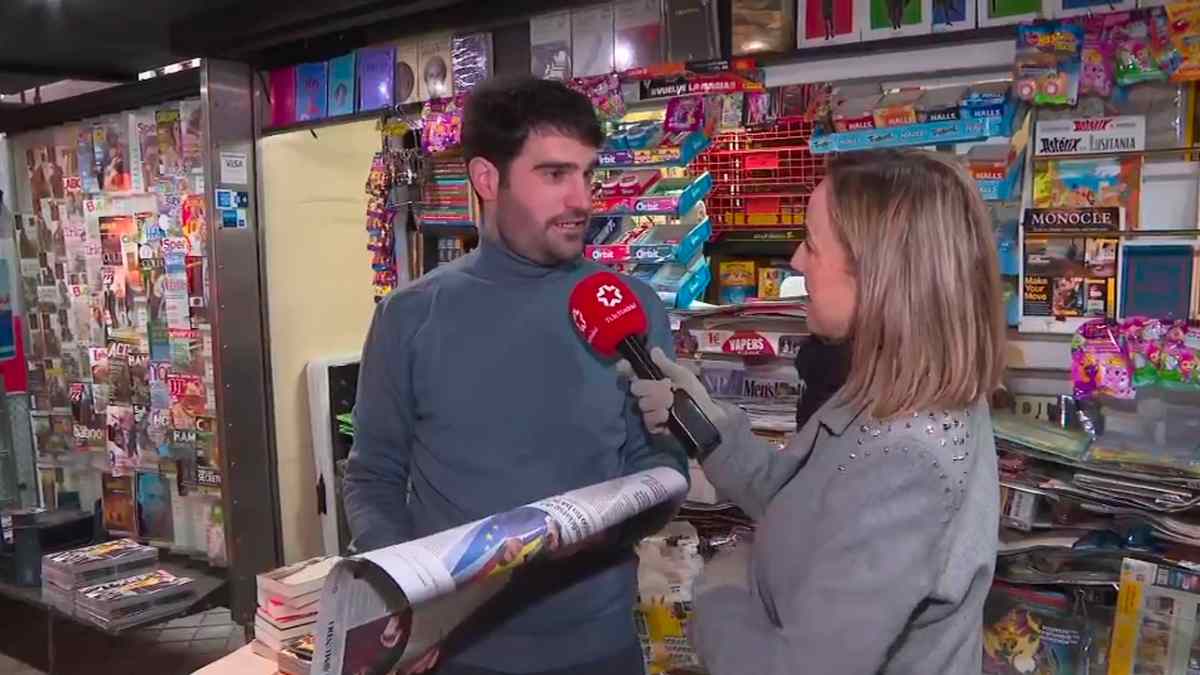 Quiosquero de Madrid atiende una entrevista en su quiosco rodeado de libros y prensa