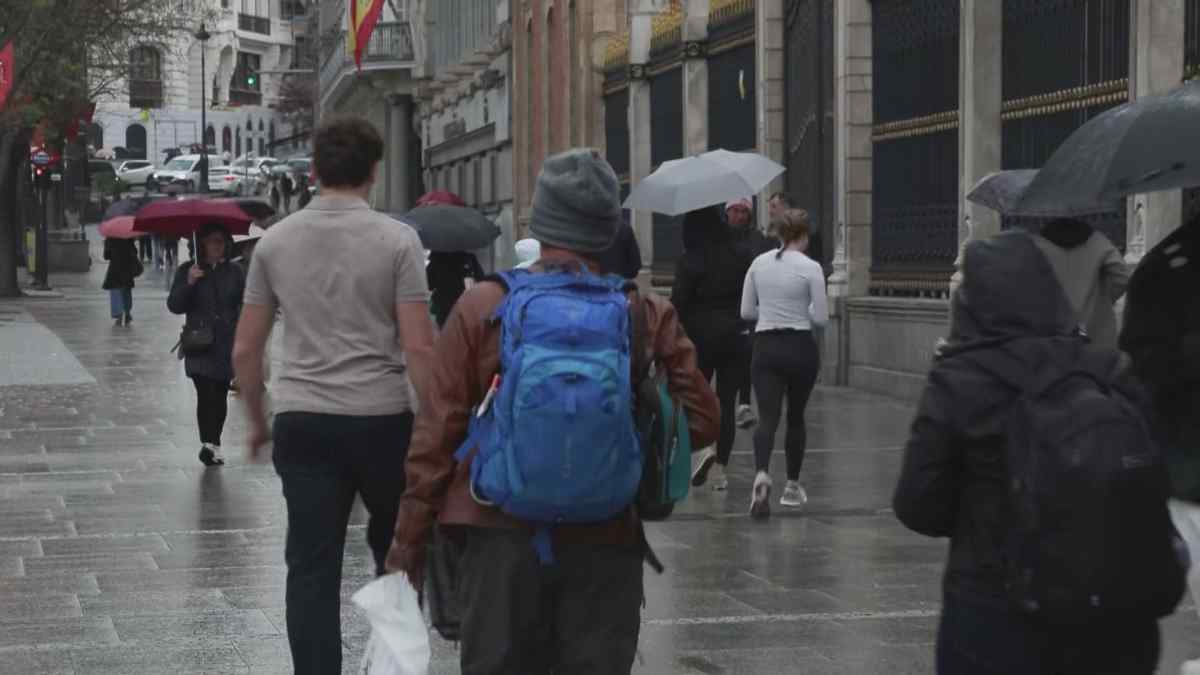 Personas caminando bajo la lluvia en Madrid tras aviso de la AEMET por descenso de temperaturas