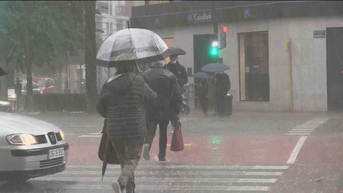Lluvia intensa en Madrid con personas cruzando la calle con paraguas tras la previsión de tormentas de AEMET