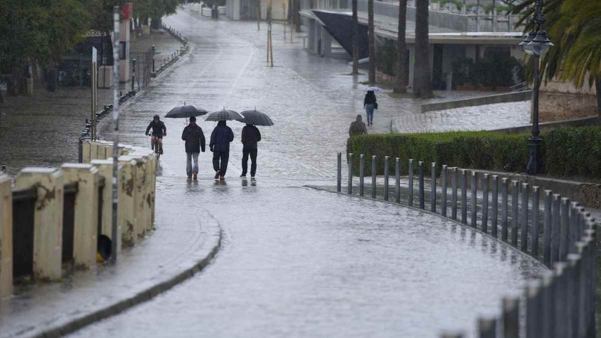 Personas caminando bajo la lluvia en Madrid durante una tarde de tormentas tras el aviso de la AEMET
