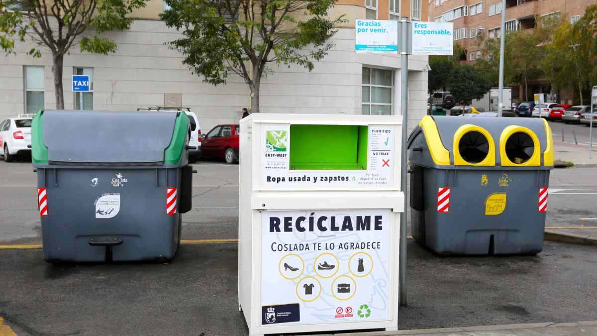 Contenedor de ropa usada en la calle junto a otros contenedores de reciclaje en España