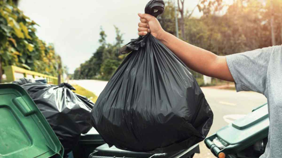 Persona tirando una bolsa de basura en un contenedor en Madrid, acción sancionada con multas si se deja fuera