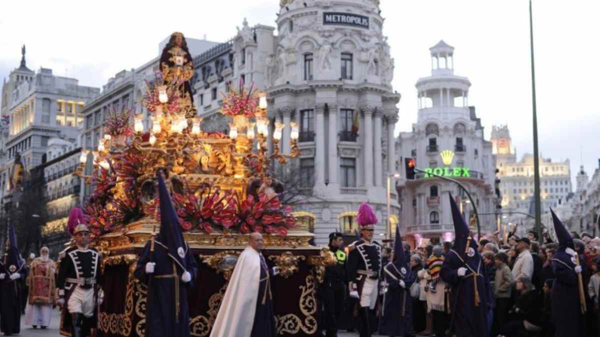 Procesión de Semana Santa 2026 en Madrid pasando por el edificio Metrópolis con nazarenos y paso religioso