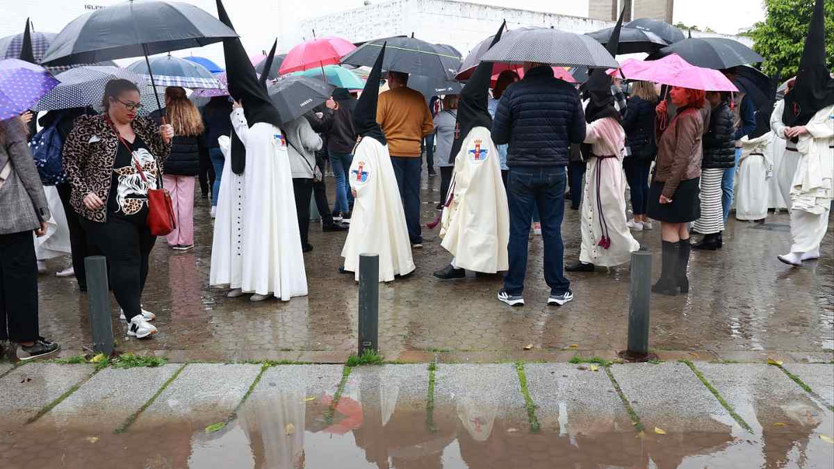 Procesión de Semana Santa en Madrid bajo la lluvia con nazarenos y público con paraguas
