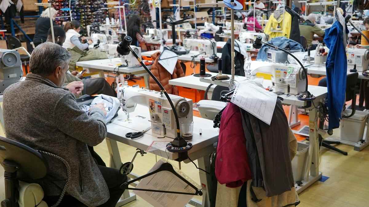 trabajadores en taller de confección textil cosiendo ropa subida salarial 2026