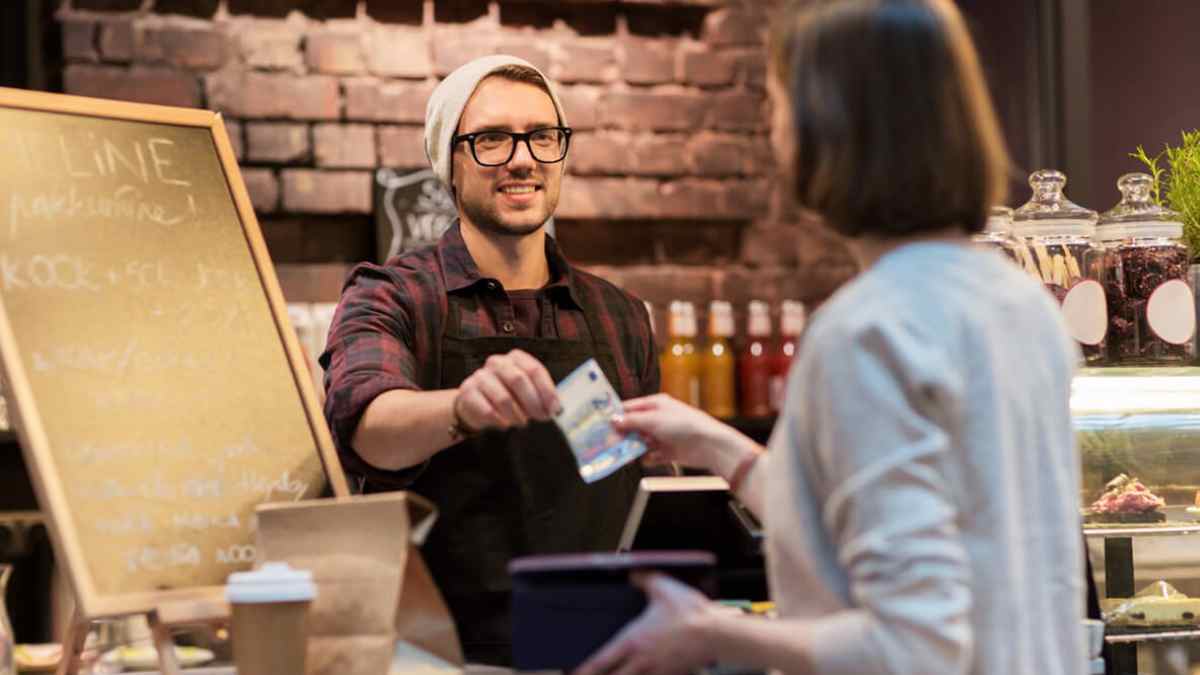 Cliente pagando con tarjeta en una tienda mientras el comercio puede exigir pago en efectivo