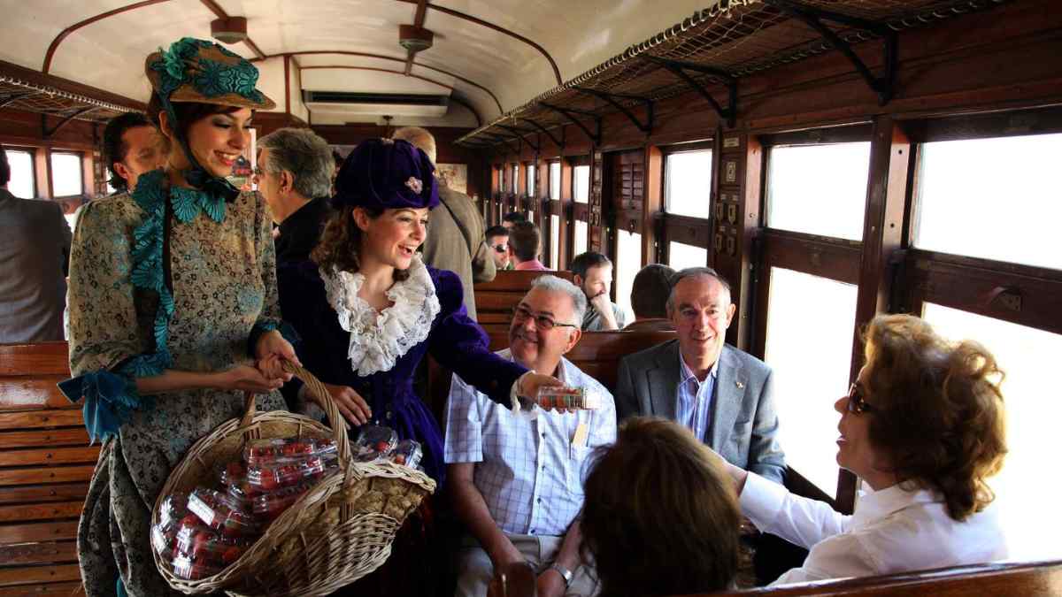 Pasajeros recibiendo fresas en el Tren de la Fresa durante el viaje histórico entre Madrid y Aranjuez