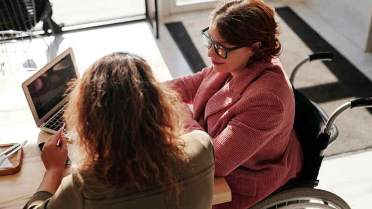 Estudiante con discapacidad en silla de ruedas recibiendo ayuda para estudios universitarios en Madrid