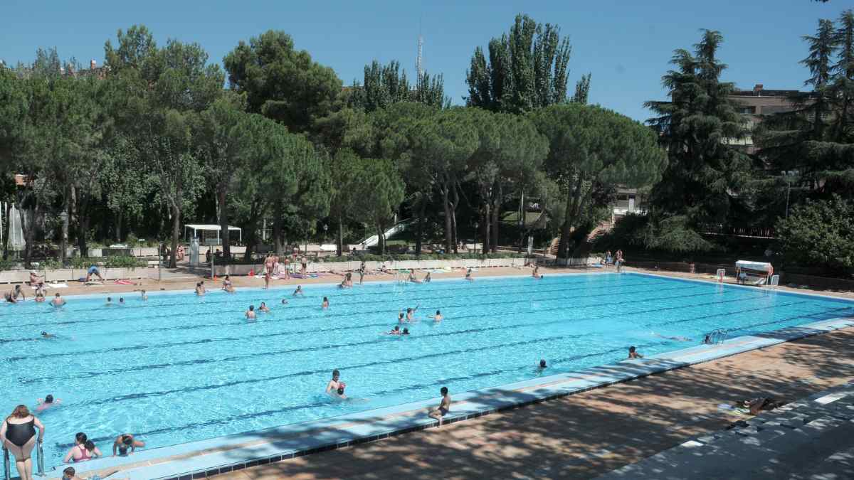 Piscina municipal de Madrid en verano con bañistas y zonas verdes alrededor