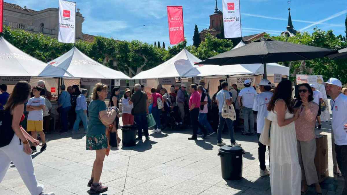 Visitantes comprando productos locales en el mercado itinerante La Despensa de Madrid en una plaza de la Comunidad de Madrid