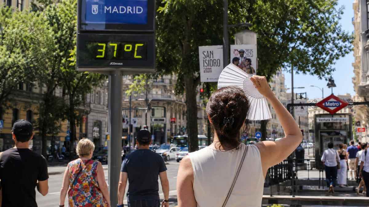 Mujer abanicándose en una calle de Madrid junto a un termómetro que marca 37 grados durante el aviso amarillo por calor