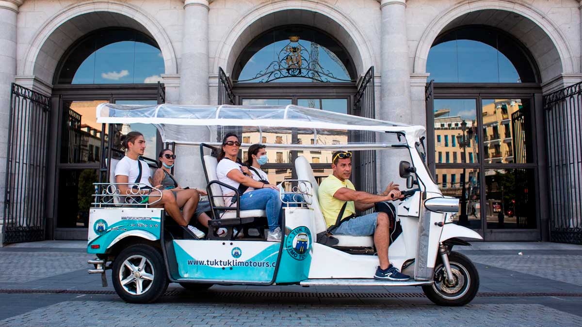 Tuk-tuk turístico en Madrid circulando frente a un edificio histórico