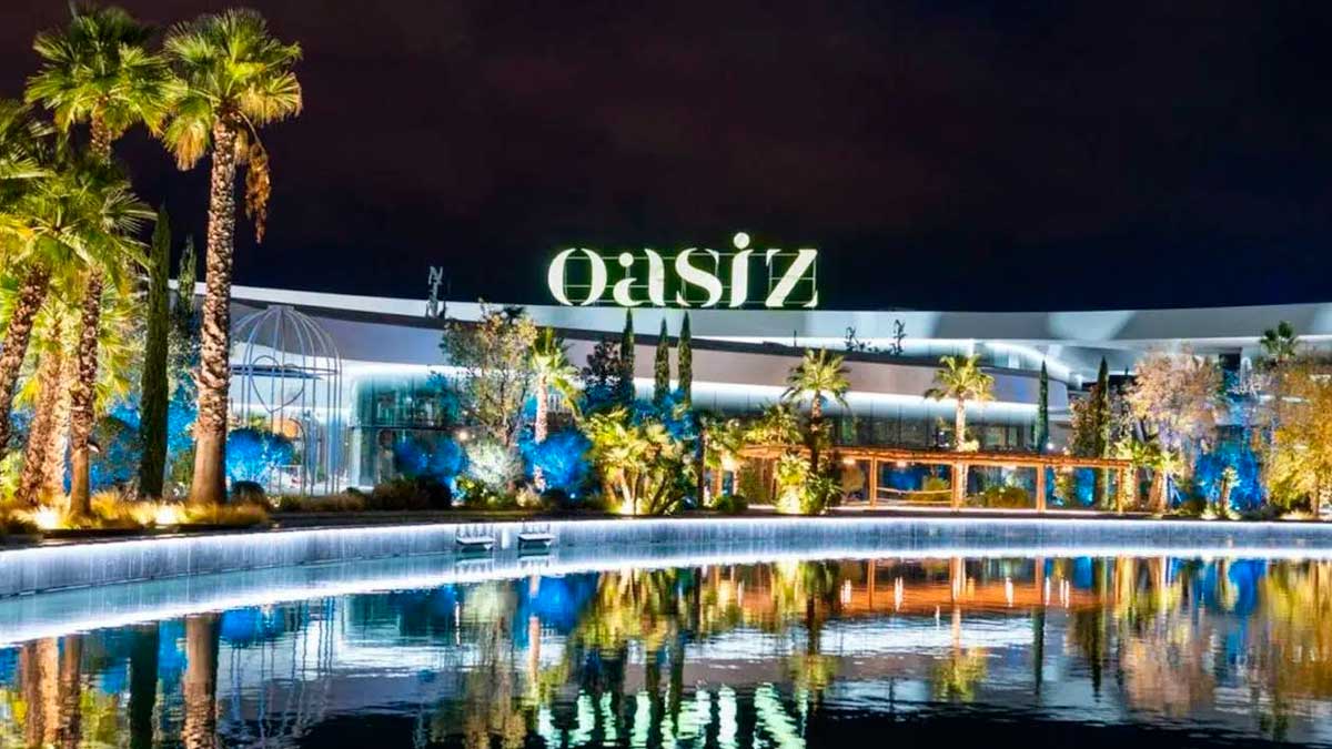 Vista nocturna de Oasiz Madrid con su lago y palmeras, ideal para descubrir nuevos restaurantes