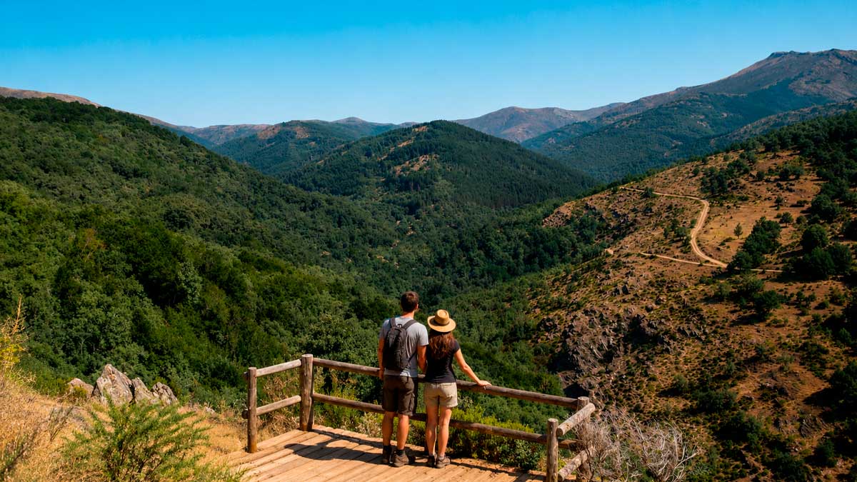 Pareja disfruta de una ruta accesible en la Sierra Norte de Madrid con vistas a montañas y bosques.