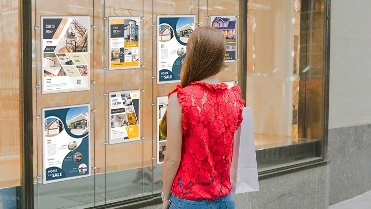 Mujer observa escaparate de inmobiliaria con anuncios de vivienda de segunda mano en Madrid