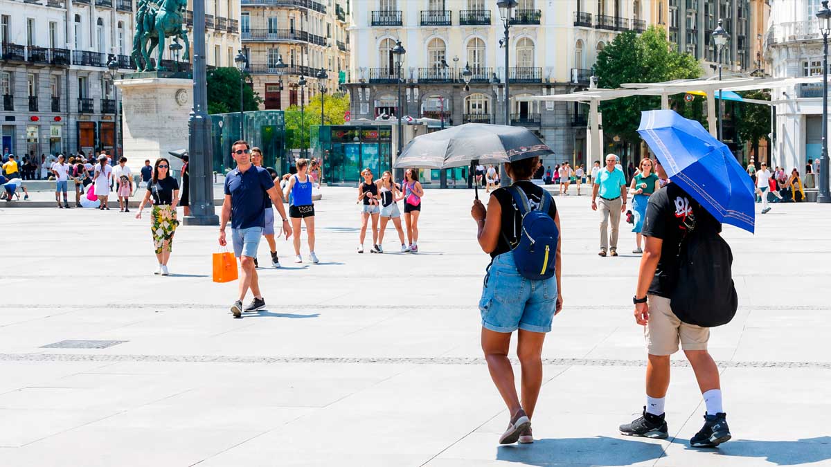 Personas con paraguas bajo el sol en Madrid durante alerta amarilla por calor extremo