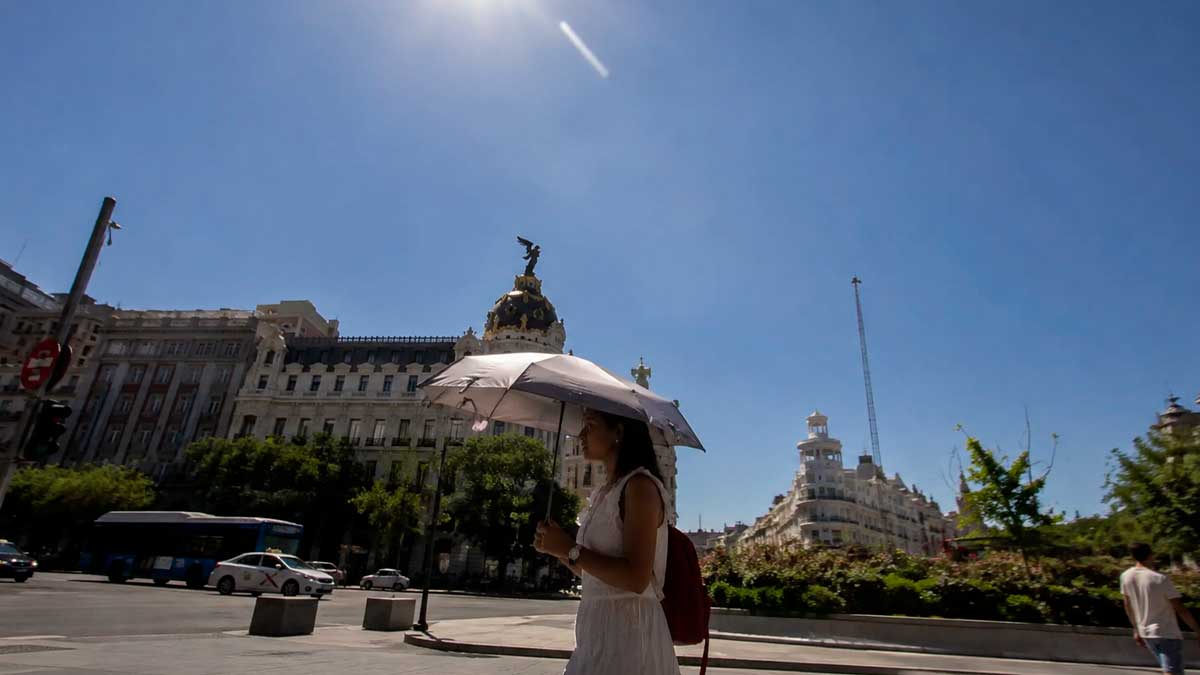 Aviso amarillo en Madrid por calor extremo, persona con paraguas bajo el sol intenso