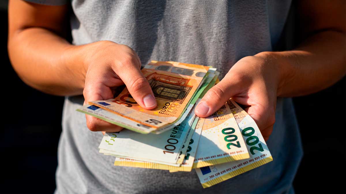 Persona sosteniendo billetes de euro para ilustrar las ayudas de hasta 1.200 euros para vivienda en Navas del Rey.