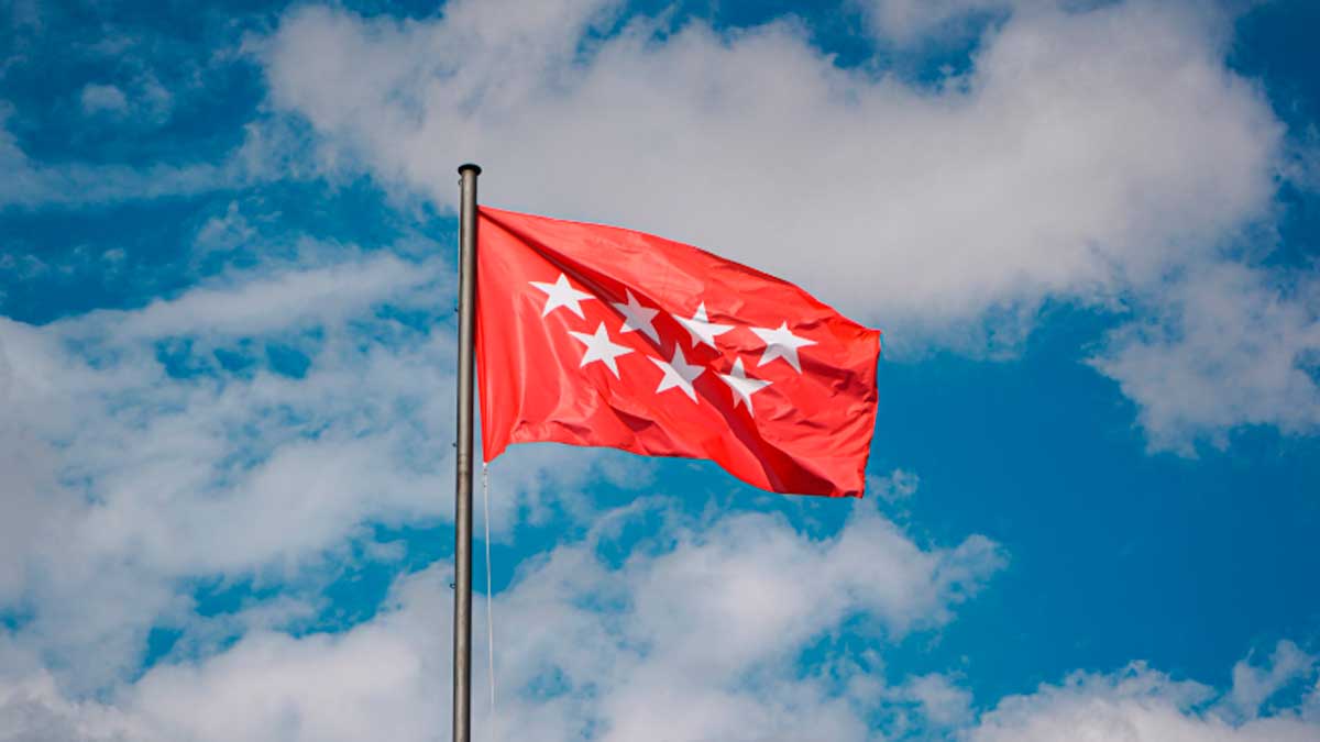 Bandera de Madrid ondeando al viento bajo un cielo azul, historia y significado