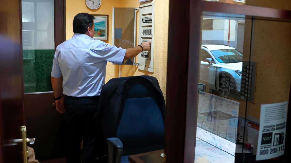 Portero en la casa del portero revisando panel eléctrico, reformas y financiación en comunidades