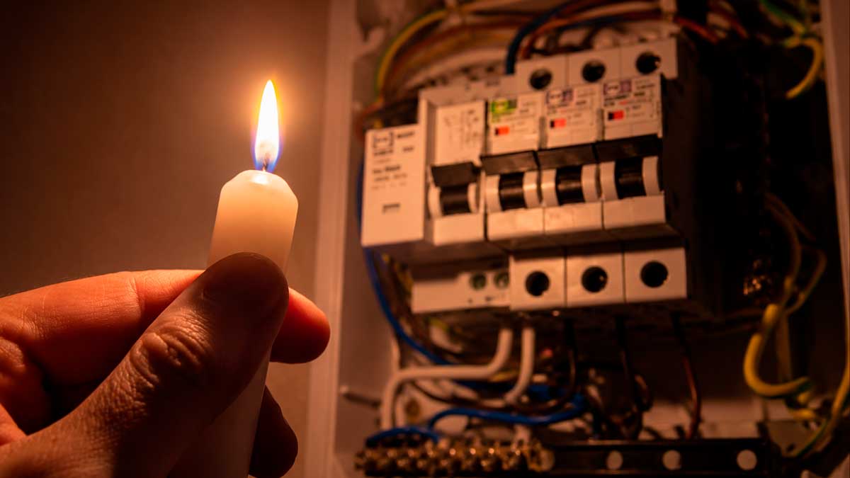 Cortes de luz en Madrid: persona con vela frente a cuadro eléctrico durante apagón