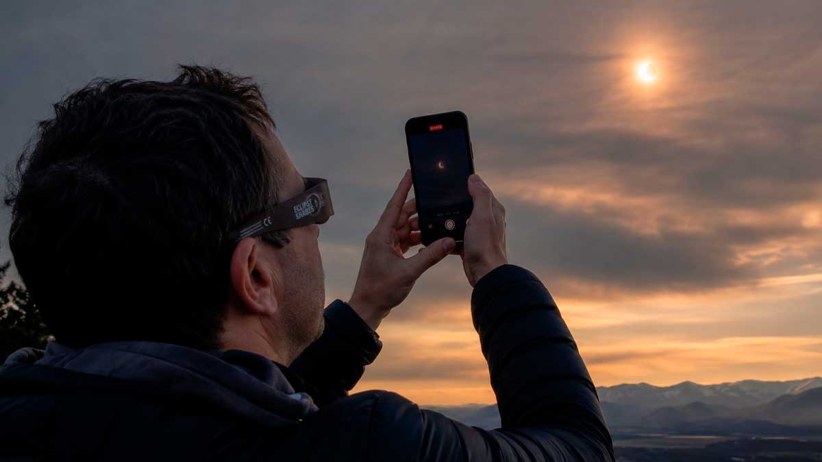 Persona fotografiando el eclipse solar en Madrid con su móvil durante el atardecer