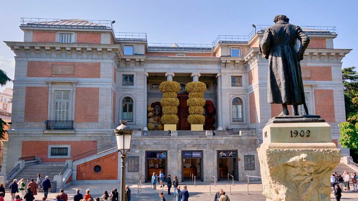Fachada del Museo del Prado en Madrid con visitantes y esculturas florales, exposiciones en Madrid