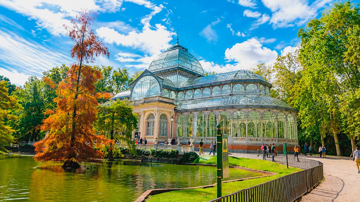 Palacio de Cristal en el Parque del Retiro, Patrimonio UNESCO, rodeado de árboles y lago