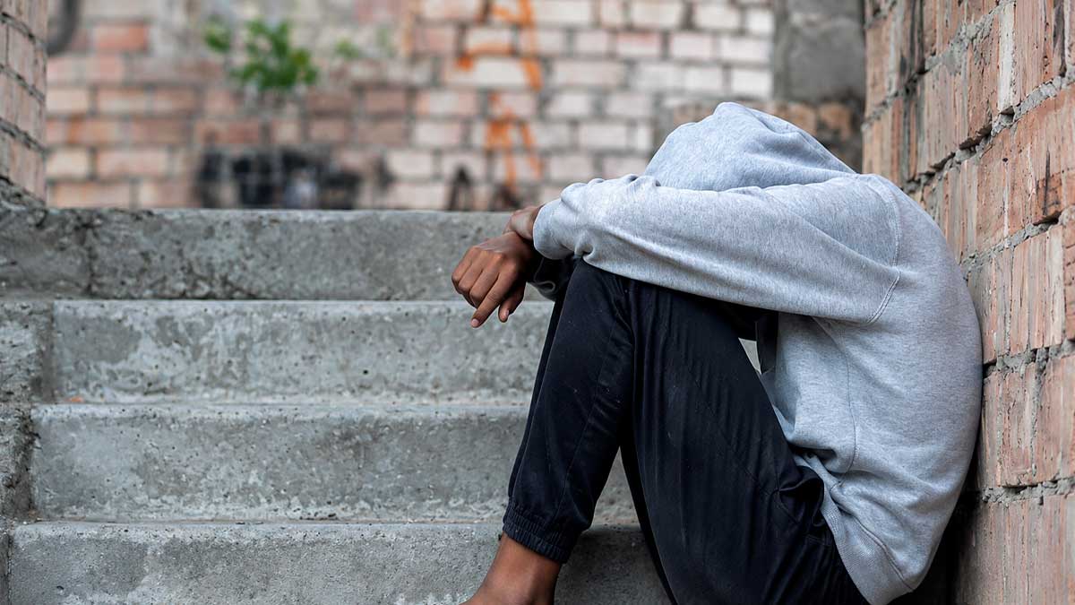 Joven sin hogar sentado en una escalera, tema de jóvenes sin hogar en Madrid